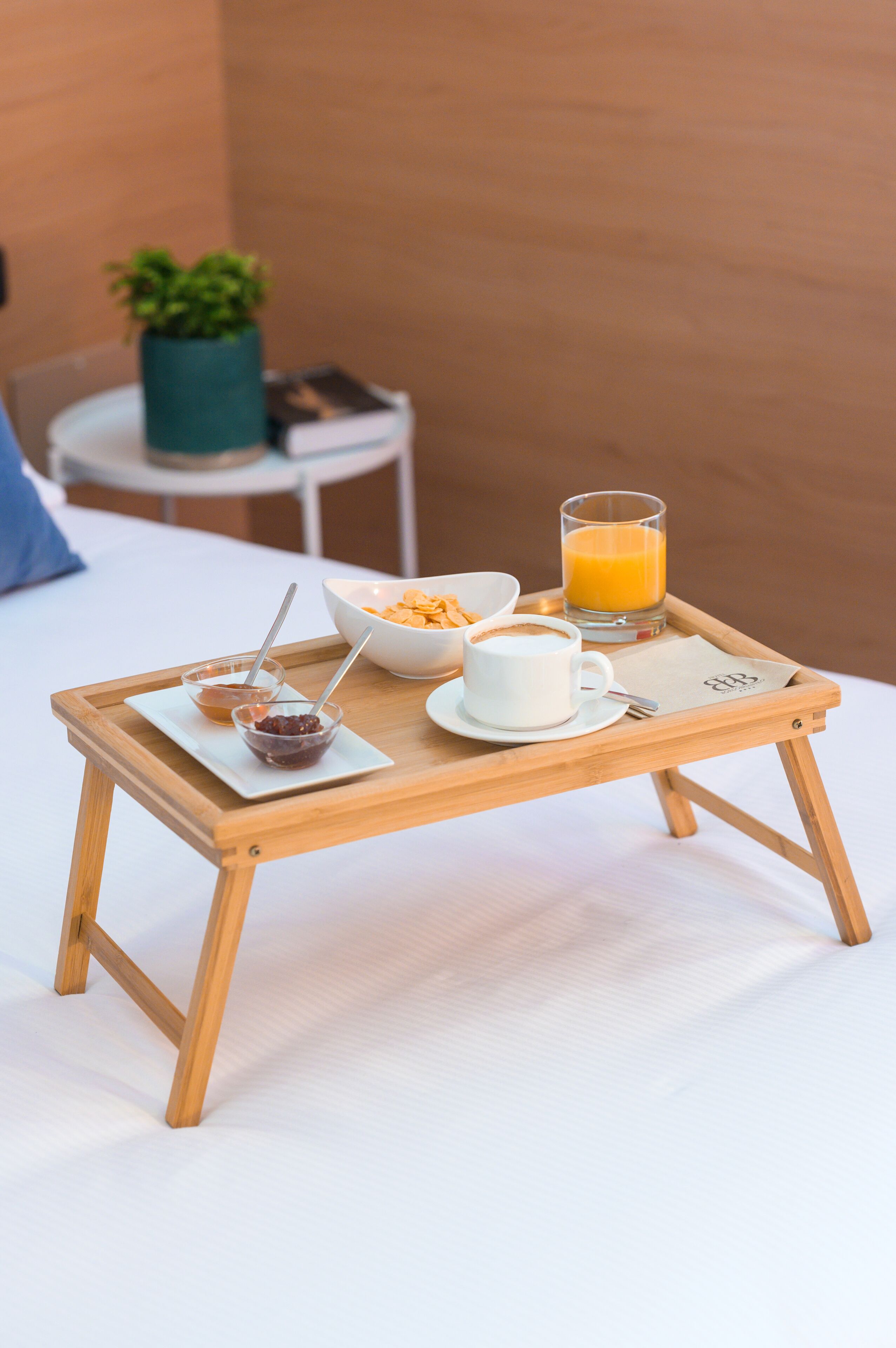 A wooden tray with breakfast items on a bed.