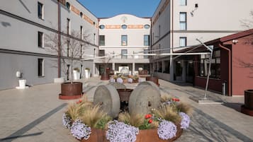 A courtyard with a central fountain, surrounded by flower beds and potted plants.