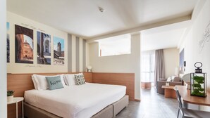 A modern hotel room with a large bed, a desk, and a seating area.