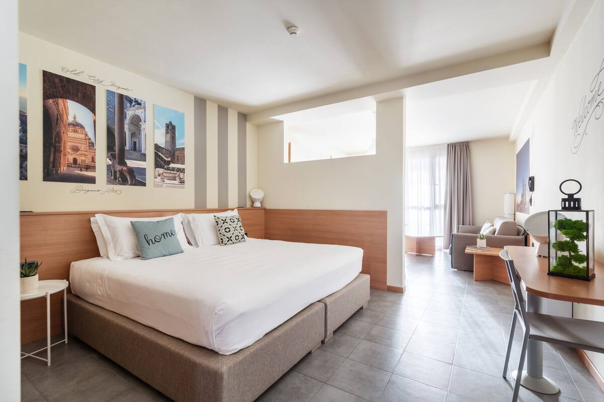Una habitación de hotel moderna con una cama grande, un escritorio y una zona de estar.