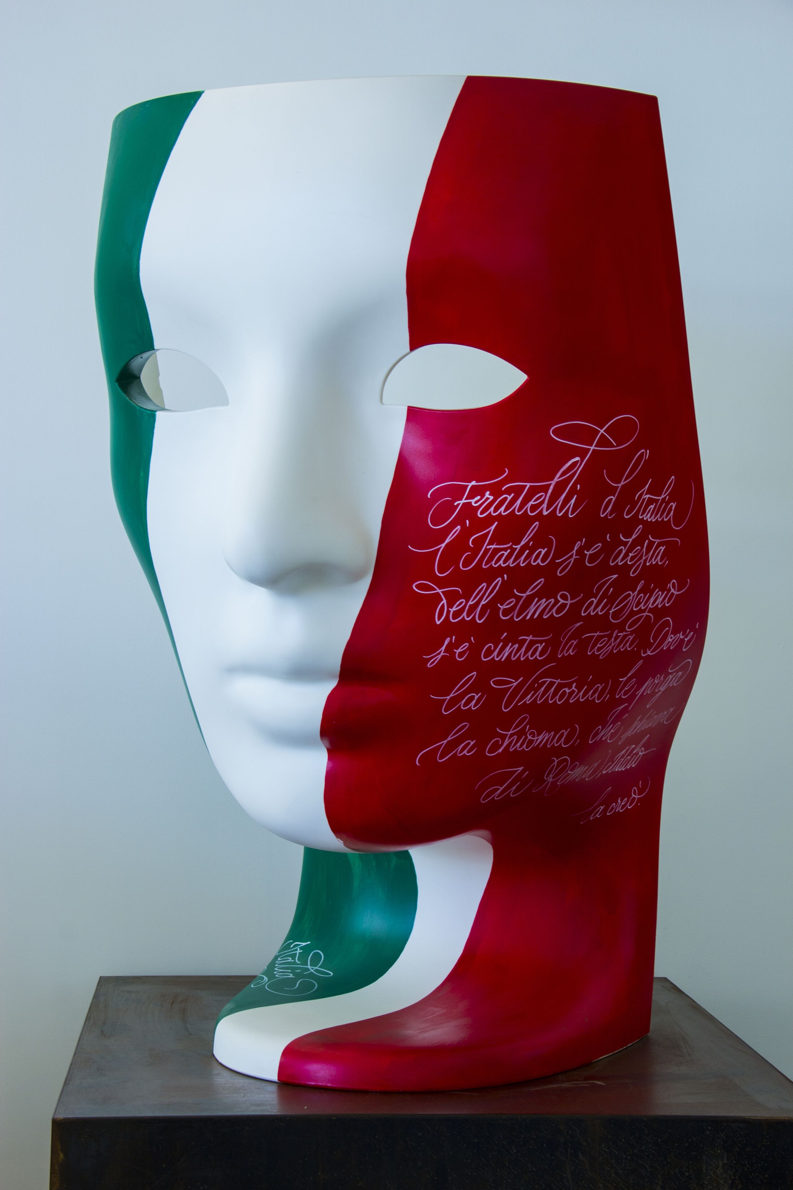 Una escultura con un rostro y texto en italiano.