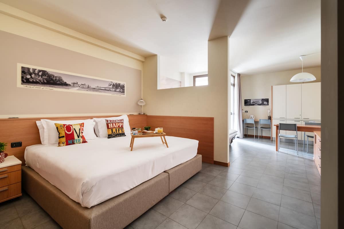Una habitación de hotel moderna con una cama grande, un escritorio y un área de comedor.