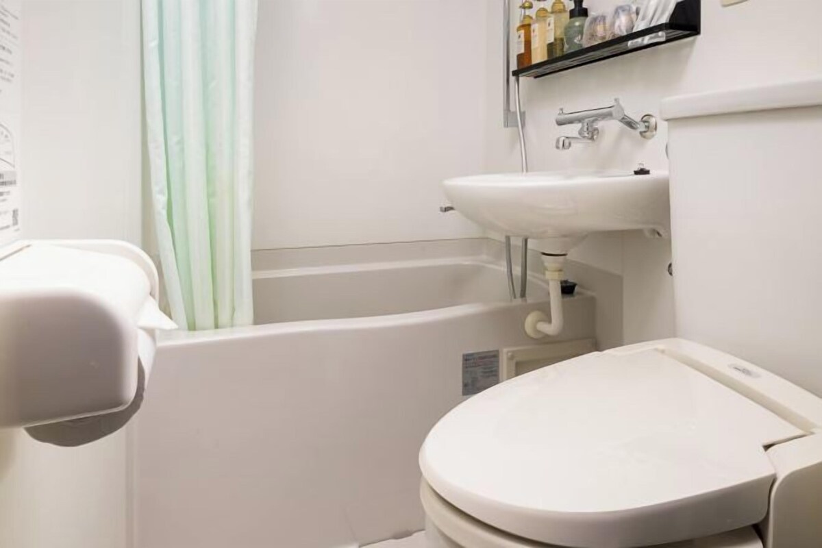 Une salle de bain équipée de toilettes, d’un lavabo, d’une baignoire et d’un rideau de douche.
