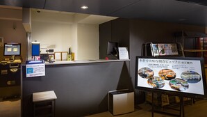 A reception desk with a digital menu display, a computer, and a small seating area. - Hotel Oak Shizuoka (Shizuoka)