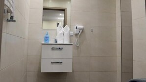 A modern bathroom with a wooden floor, a white vanity with a mirror, a towel rack, and a shower area. - Helios Apartamenty (Ustka)