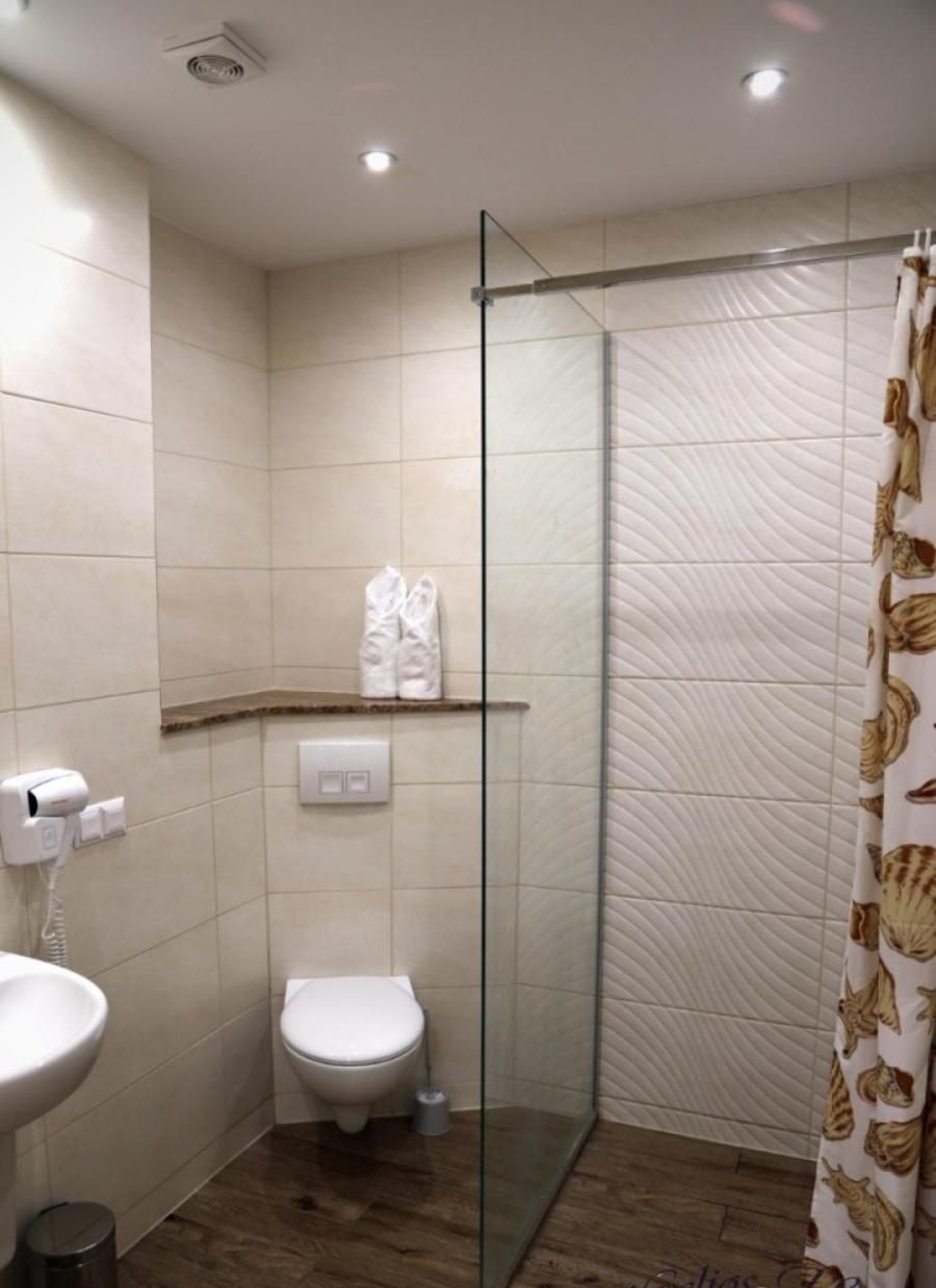 A bathroom with a glass shower enclosure, a toilet, a sink, and a towel rack.