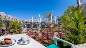 A terrace with a table set for a meal, surrounded by palm trees and a clear blue sky. - Hotel LIVVO Los Calderones - Adults Recommended (San Bartolomé de Tirajana)