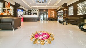 Un vestíbulo de hotel con una recepción, zona de estar y un arreglo floral decorativo en el suelo.