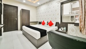 Una habitación de hotel moderna con una cama grande, un escritorio con silla, un armario y una ventana con cortinas.