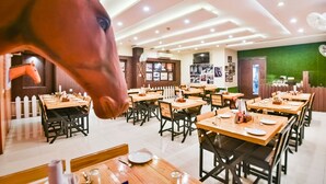 Un restaurante con mesas y sillas de madera, una cerca blanca de piquetes y una pared verde.