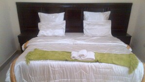 Een keurig opgemaakt bed met witte beddengoed en een groene plaid.