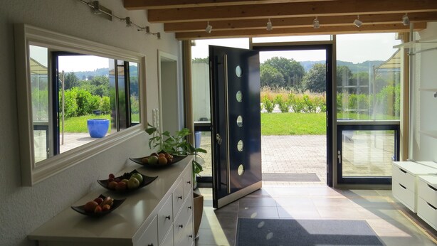 Una cocina moderna con un amplio ventanal, un frutero y una puerta que da a un espacio exterior.