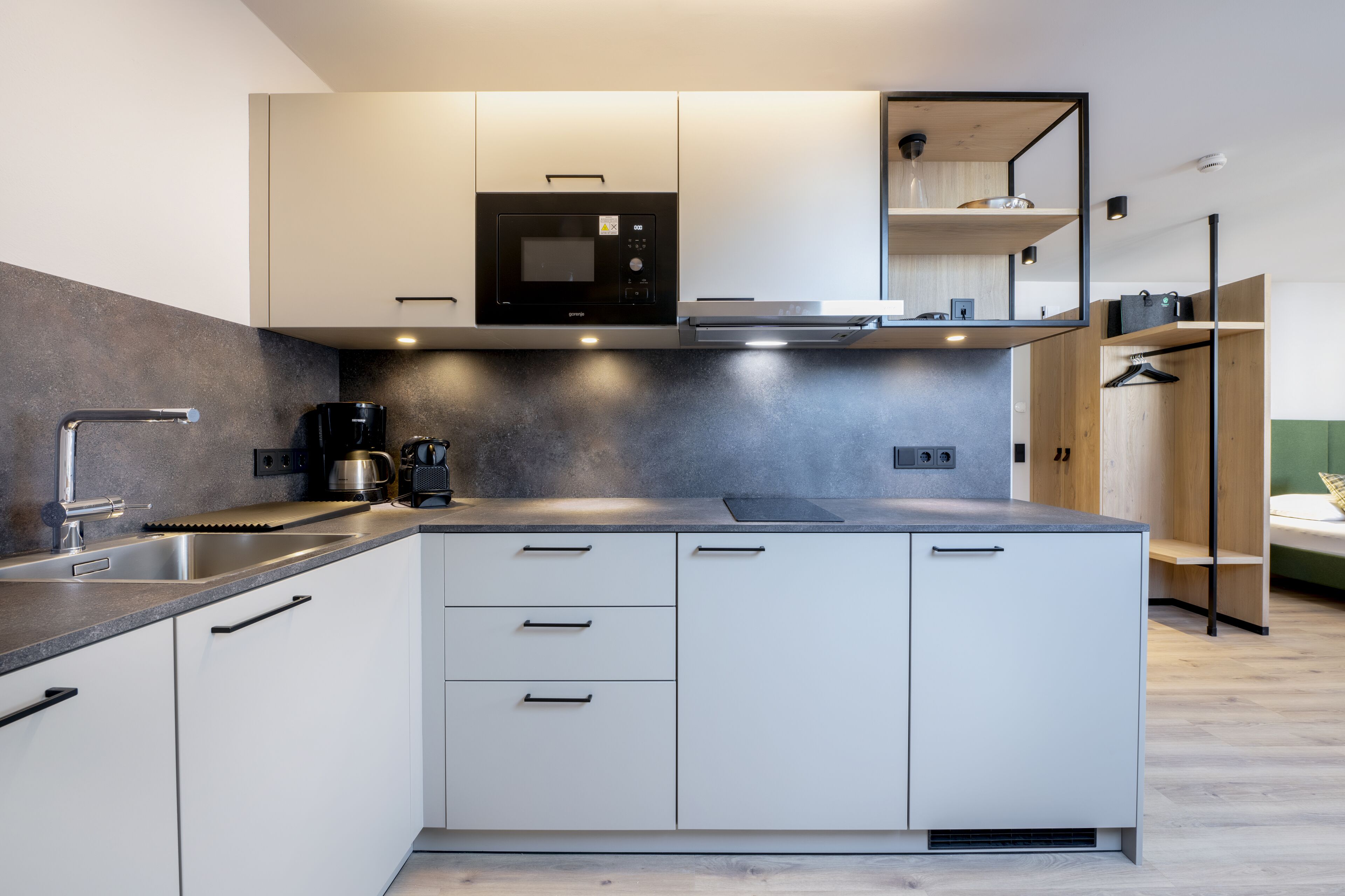 A modern kitchen with white cabinets, a built-in microwave, and a coffee maker.