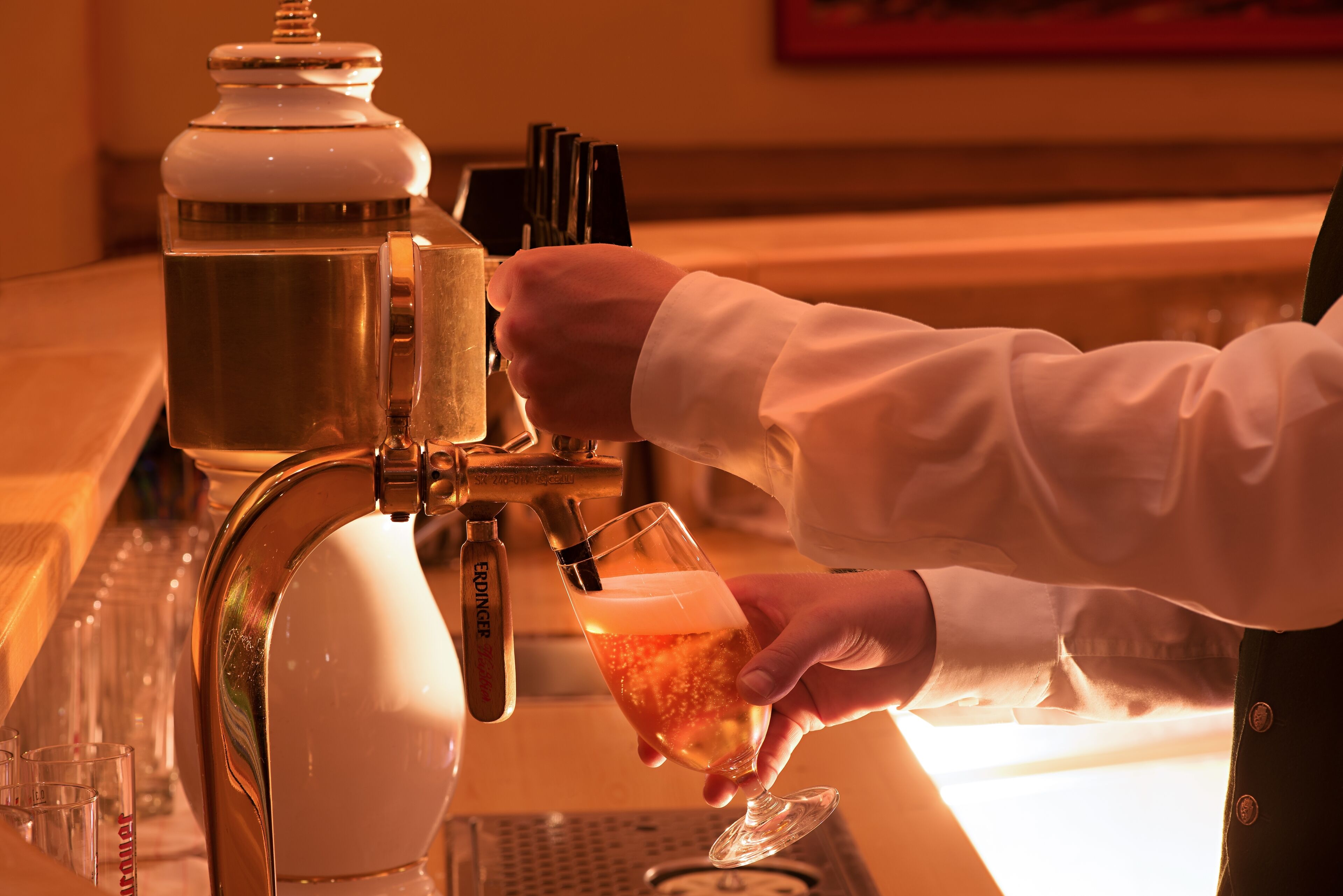 A hand pouring a drink from a tap into a glass.