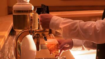A hand pouring a drink from a tap into a glass.
