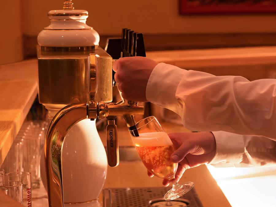 A hand pouring a drink from a tap into a glass.