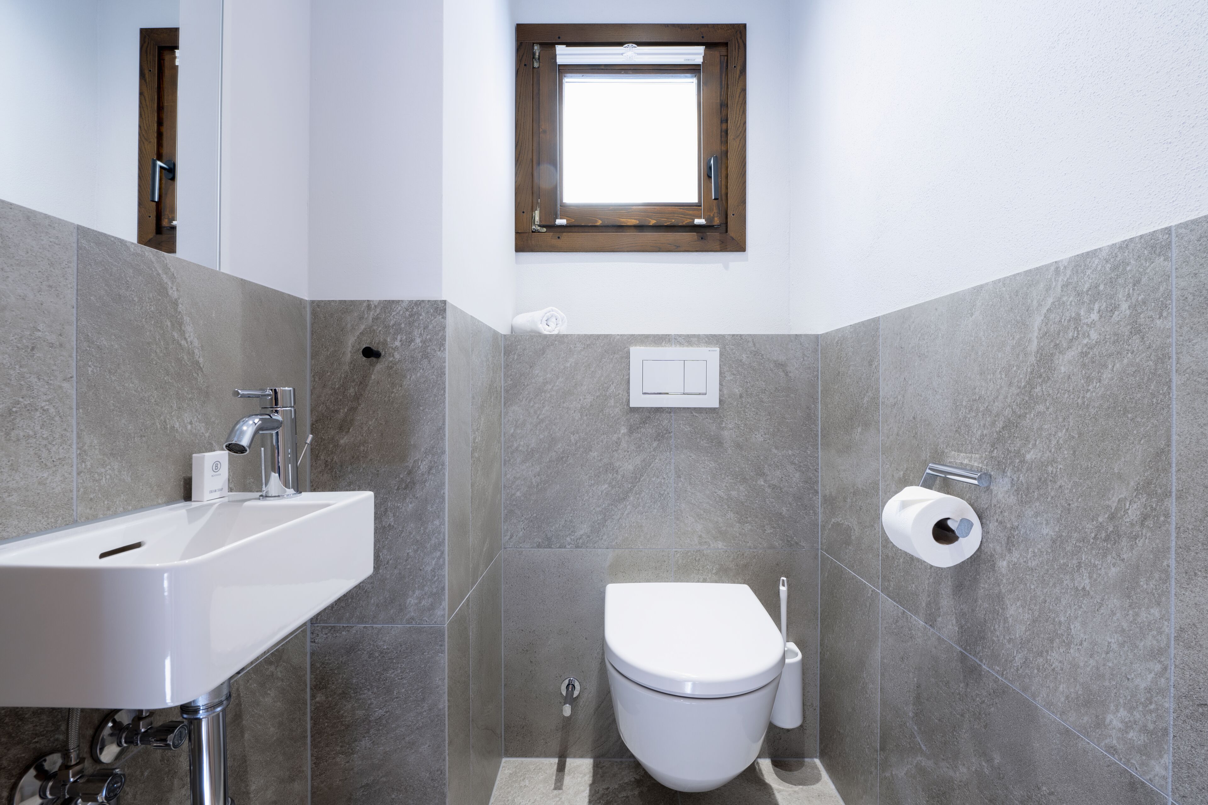 A bathroom with a white sink, a toilet, and a window.