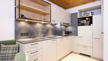 A modern kitchen with white cabinets, a wooden ceiling, and built-in appliances.