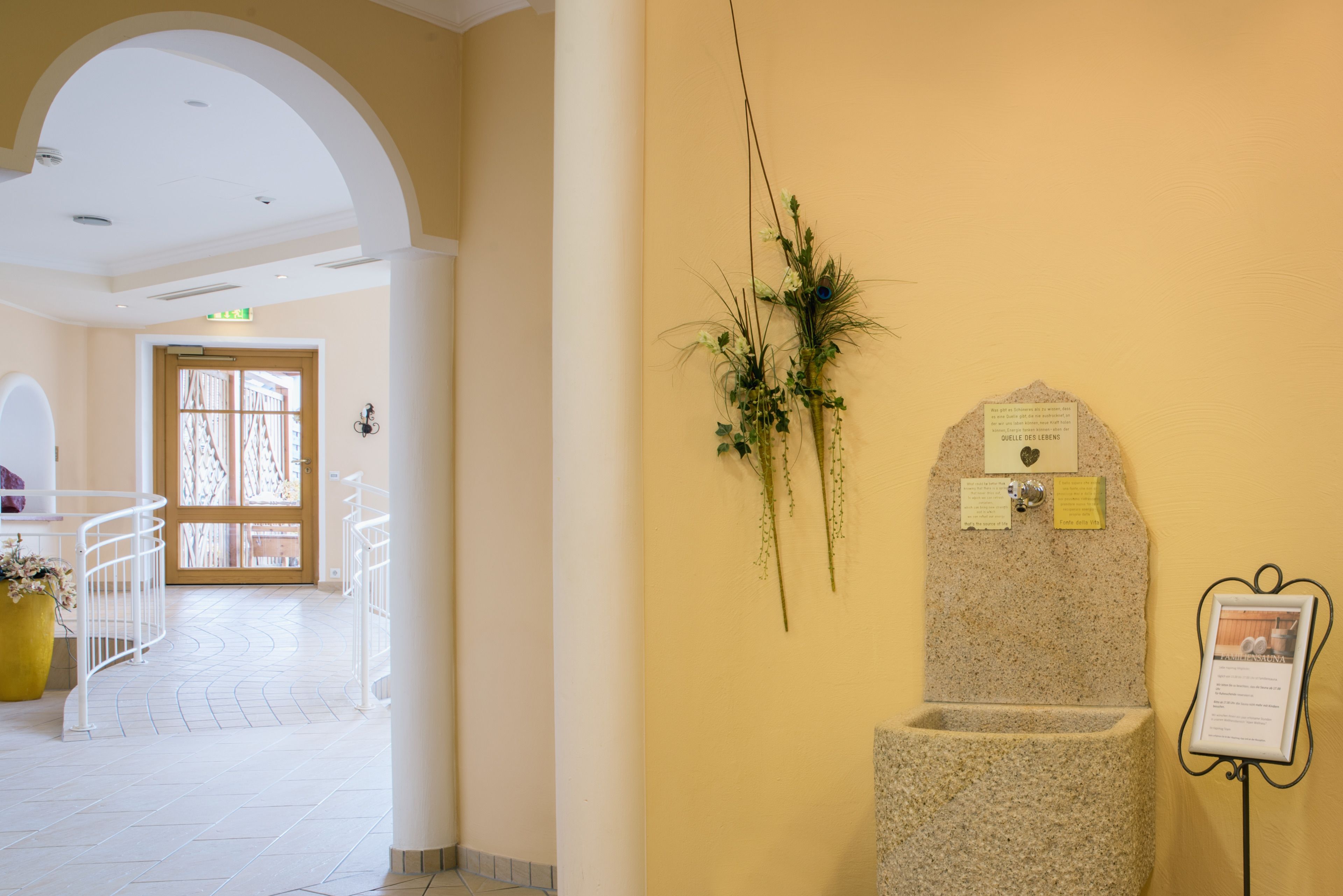 Un pasillo con una fuente de piedra, una señal en la pared y una planta en maceta.