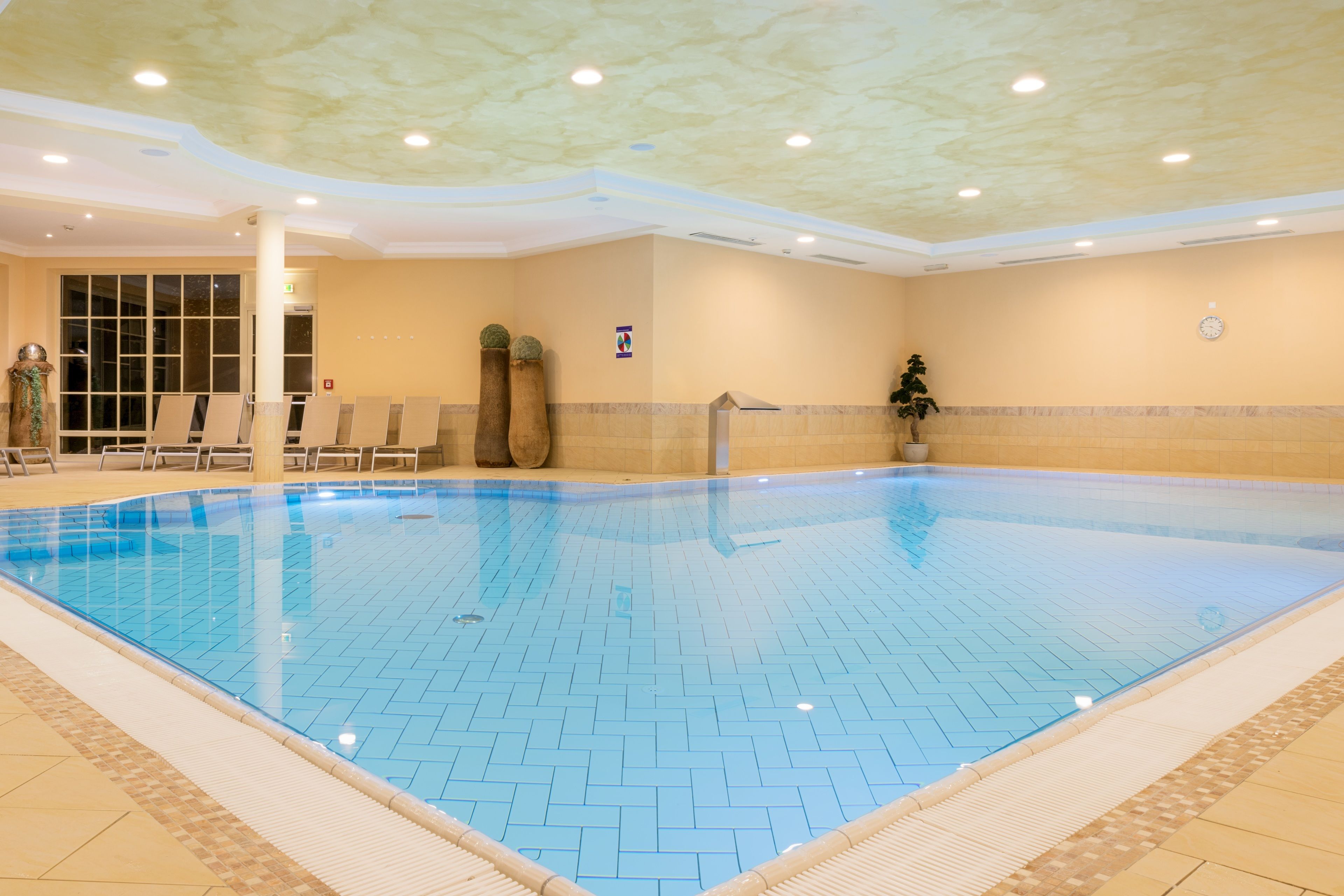Una piscina interior con paredes de azulejos e iluminación empotrada en el techo.