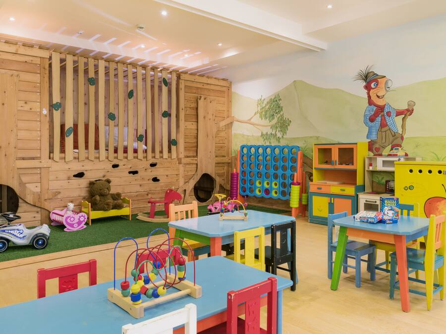 A children's playroom with a wooden climbing wall, colorful furniture, and a mural of a character.