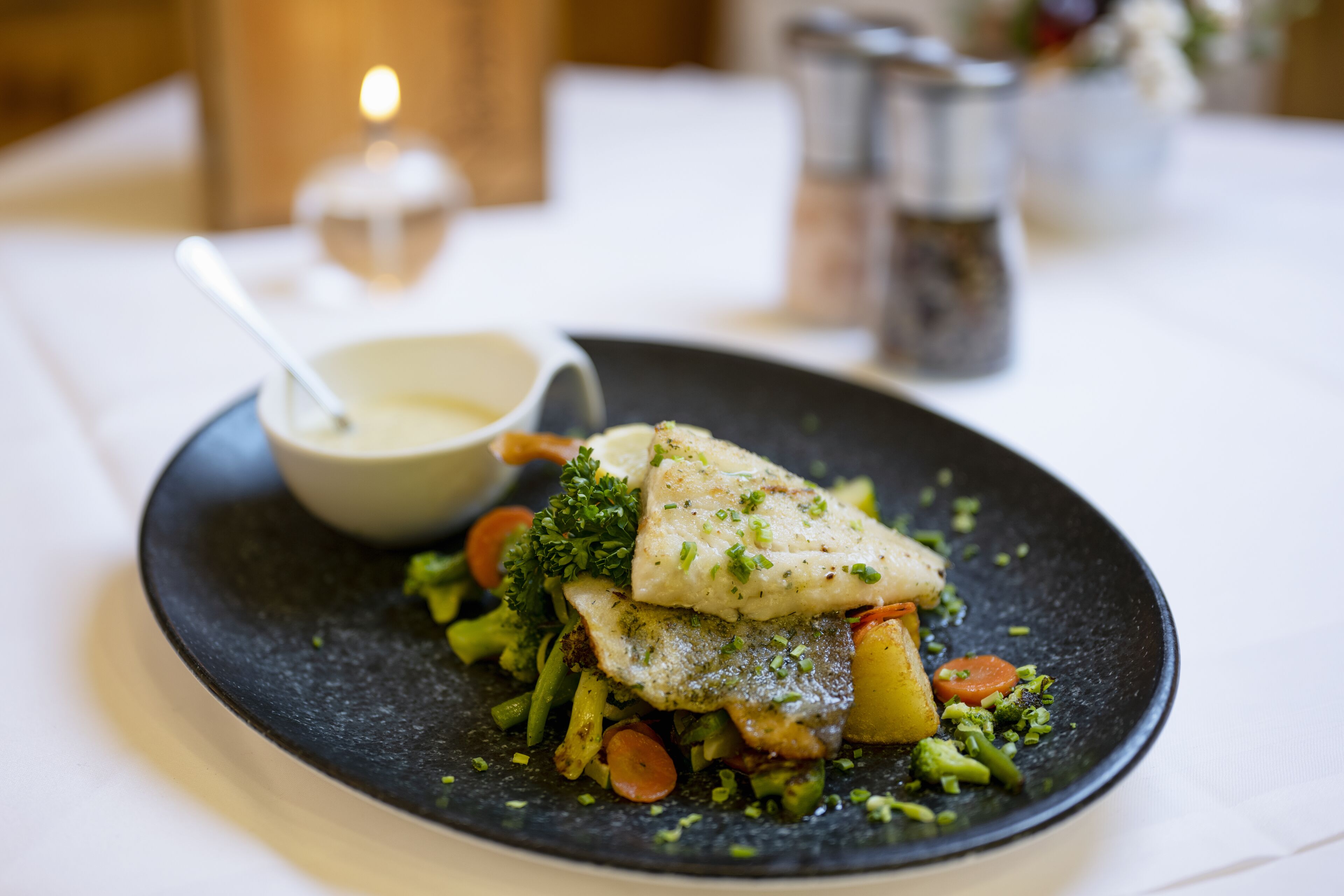 Un plato de pescado con verduras sobre un plato oscuro.