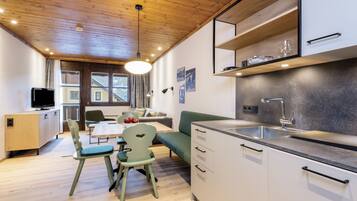 Une cuisine moderne avec un plafond en bois, un coin repas avec une table et des chaises, et un canapé vert.