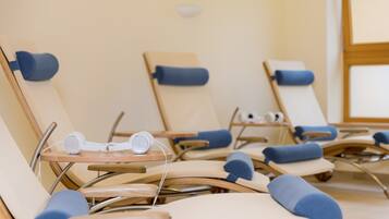 A row of sun loungers with blue cushions and a pair of white headphones on a table.