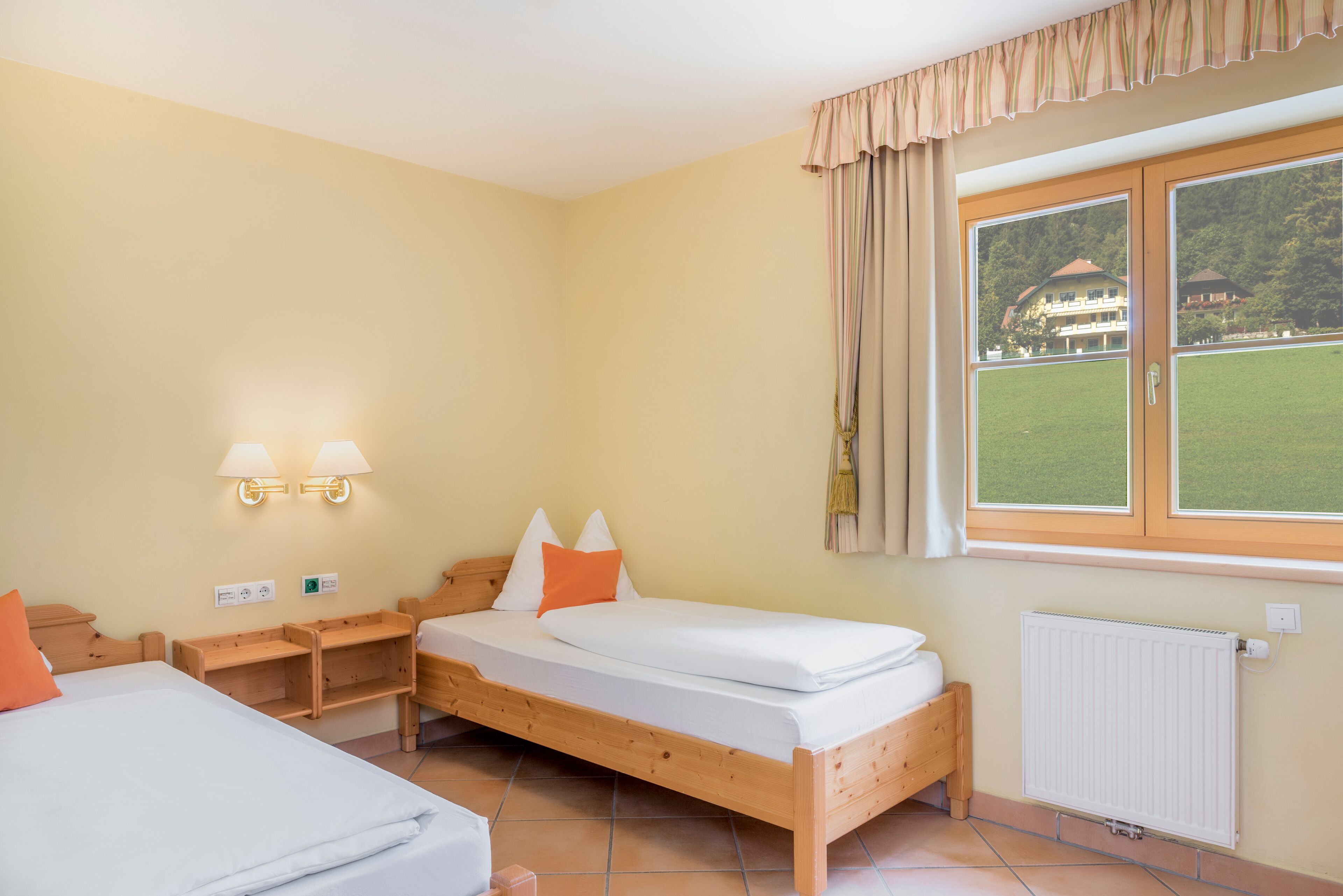 Ein Hotelzimmer mit einem hölzernen Bett, einem Nachttisch, einer Lampe und einem Fenster mit Vorhängen.
