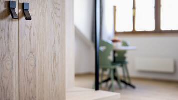 A wooden wall with a door handle and a view of a room with a table and chairs.