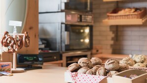 Une vitrine de boulangerie présentant diverses sortes de pains et de bretzels, un téléviseur et un comptoir en bois.