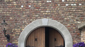 Un edificio de ladrillo con una puerta de madera grande enmarcada por un arco de piedra.