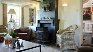 Una sala de estar acogedora con chimenea, sillones de mimbre, una mesita de centro y una planta en maceta.