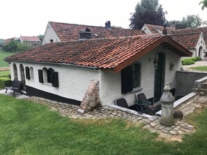 A small white building with a red-tiled roof, a stone pathway, and a bench. - B&B Het Stille Genoegen (Brakel)