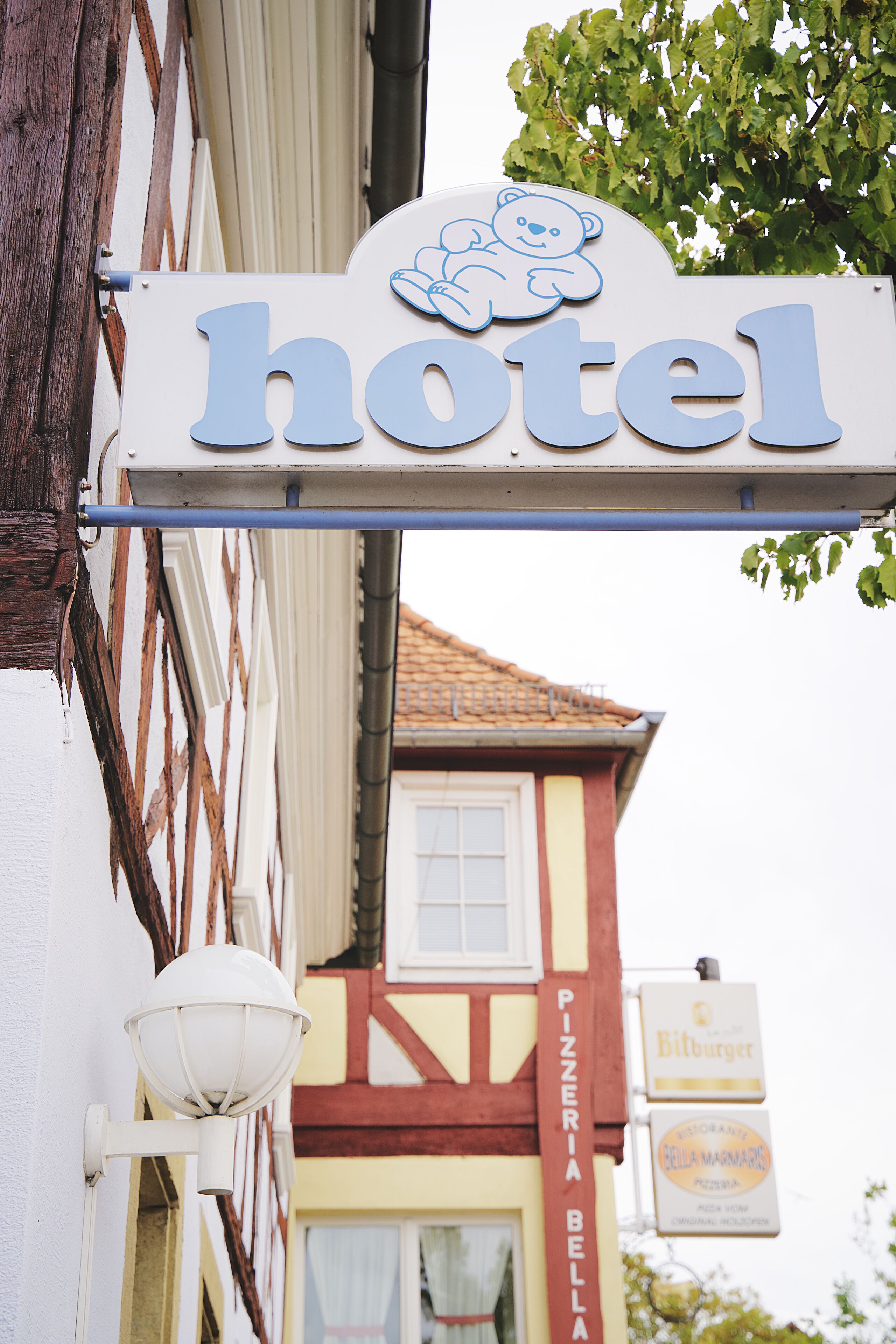 Une enseigne d’hôtel avec un logo représentant un ours et le mot « hôtel » écrit en lettres bleues.