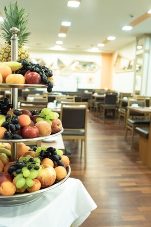 A multi-tiered fruit display in a dining area with wooden tables and chairs. - Hotel Bär Sinsheim (Sinsheim)