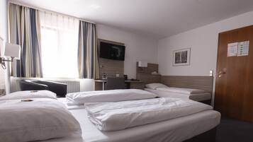 Ein Hotelzimmer mit einem Bett, einem Schreibtisch, einem Stuhl, einem Fernseher und einer Tür.
