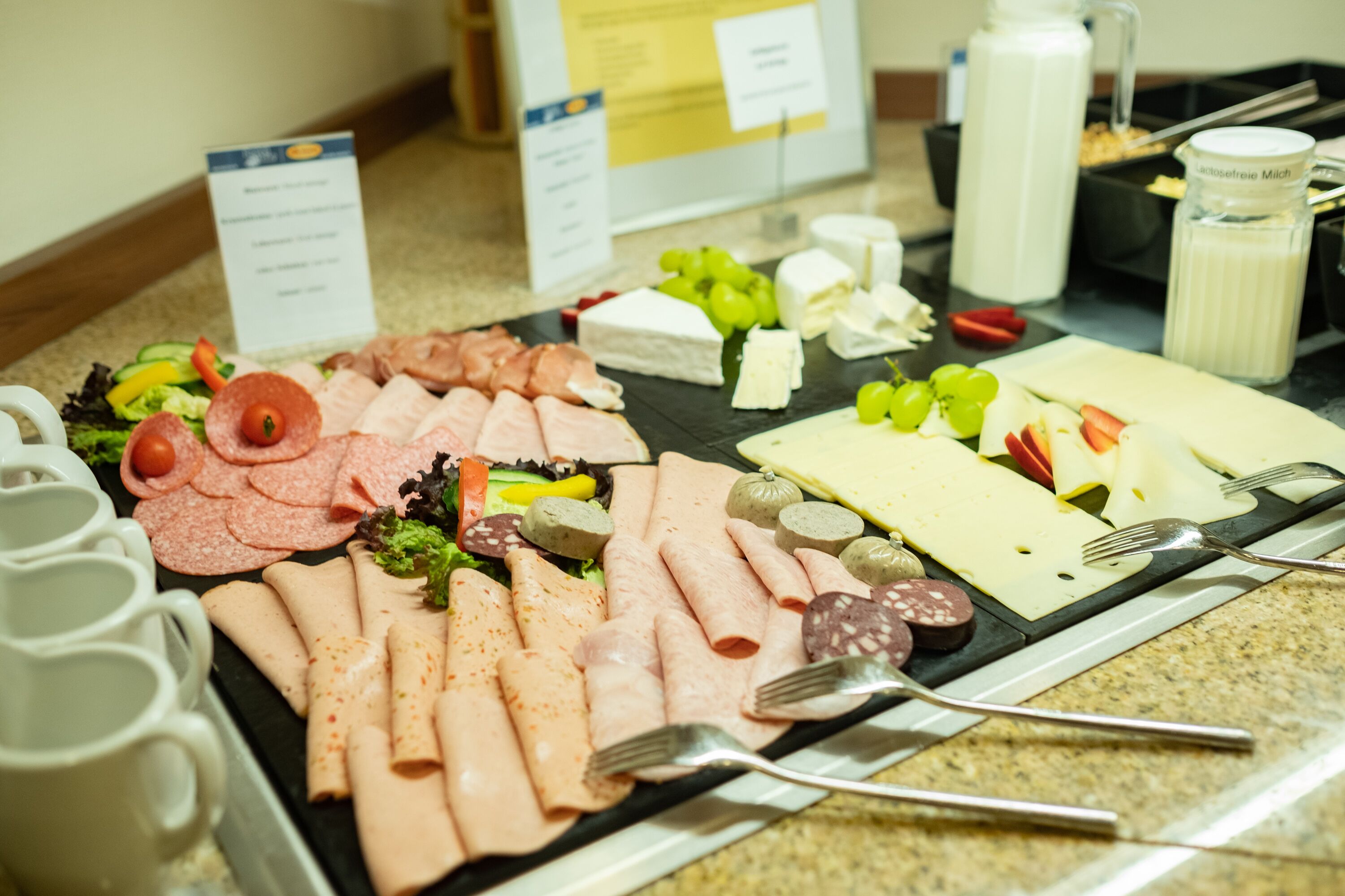 A buffet with various meats, cheeses, and fruits.