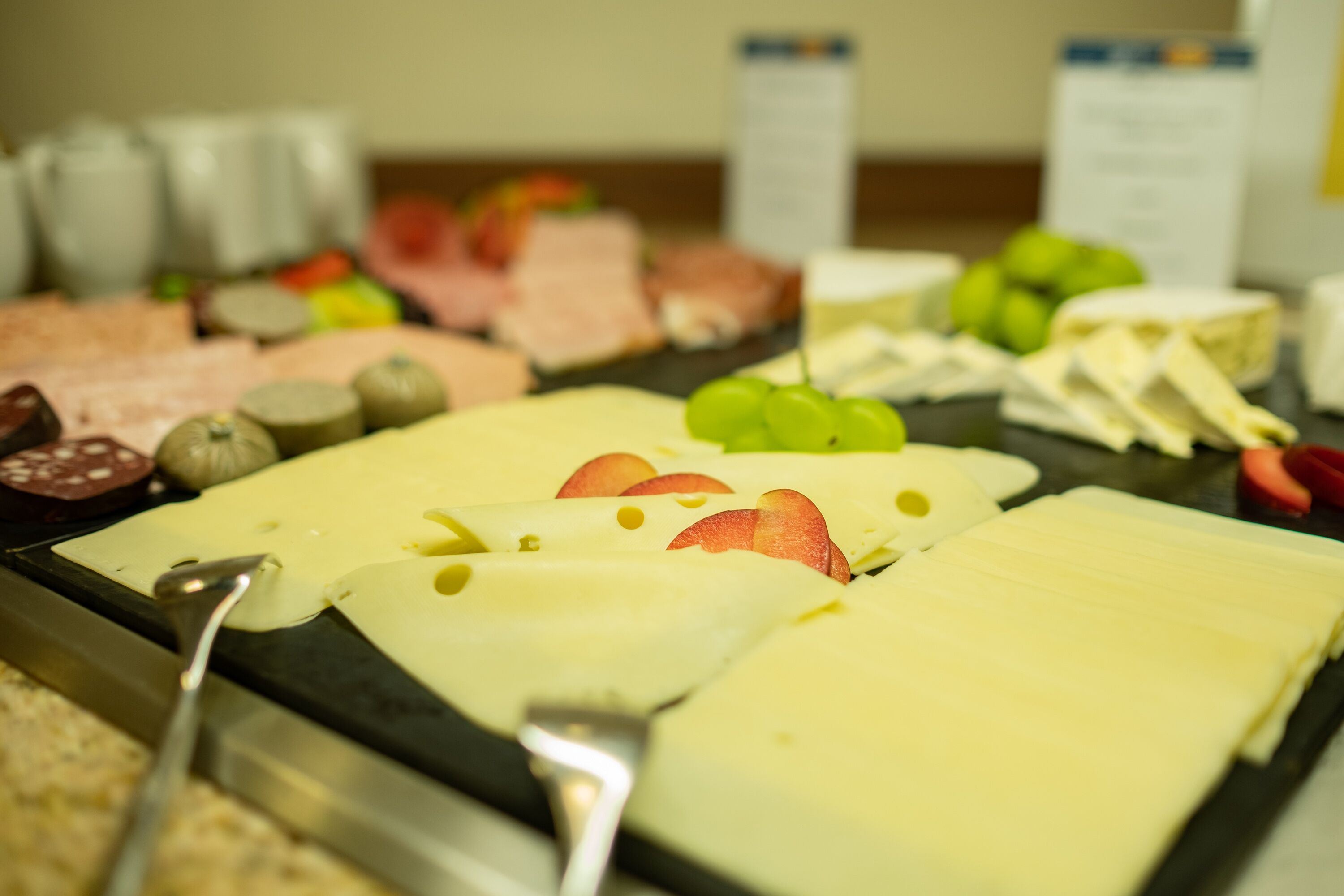 A buffet with various cheeses, fruits, and meats.