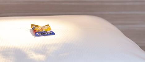 A bed with a small packet of Goldbären chocolates on it.