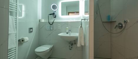 Une salle de bain moderne équipée de toilettes, d’un lavabo et d’une douche.