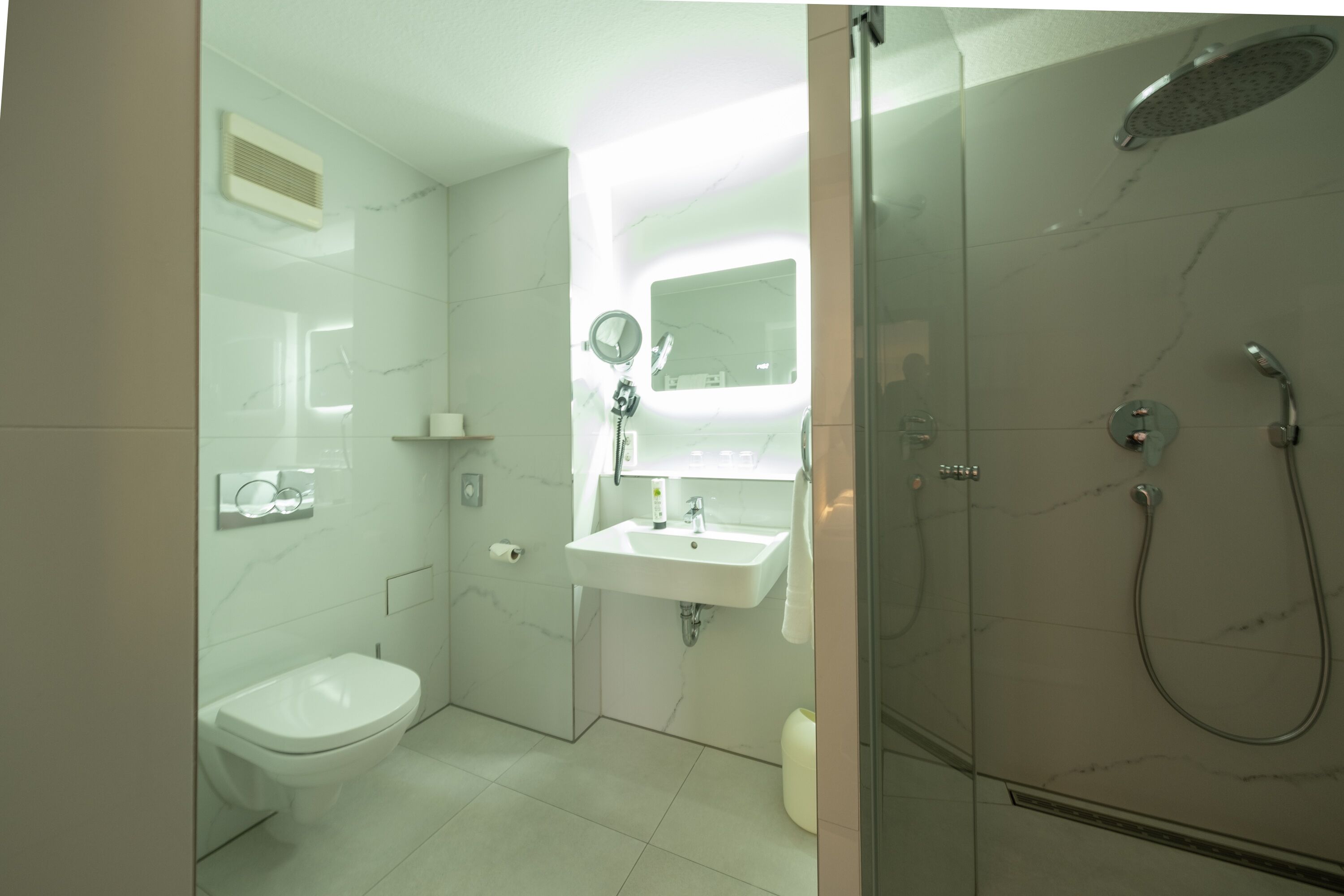 A modern bathroom with a toilet, sink, and shower.