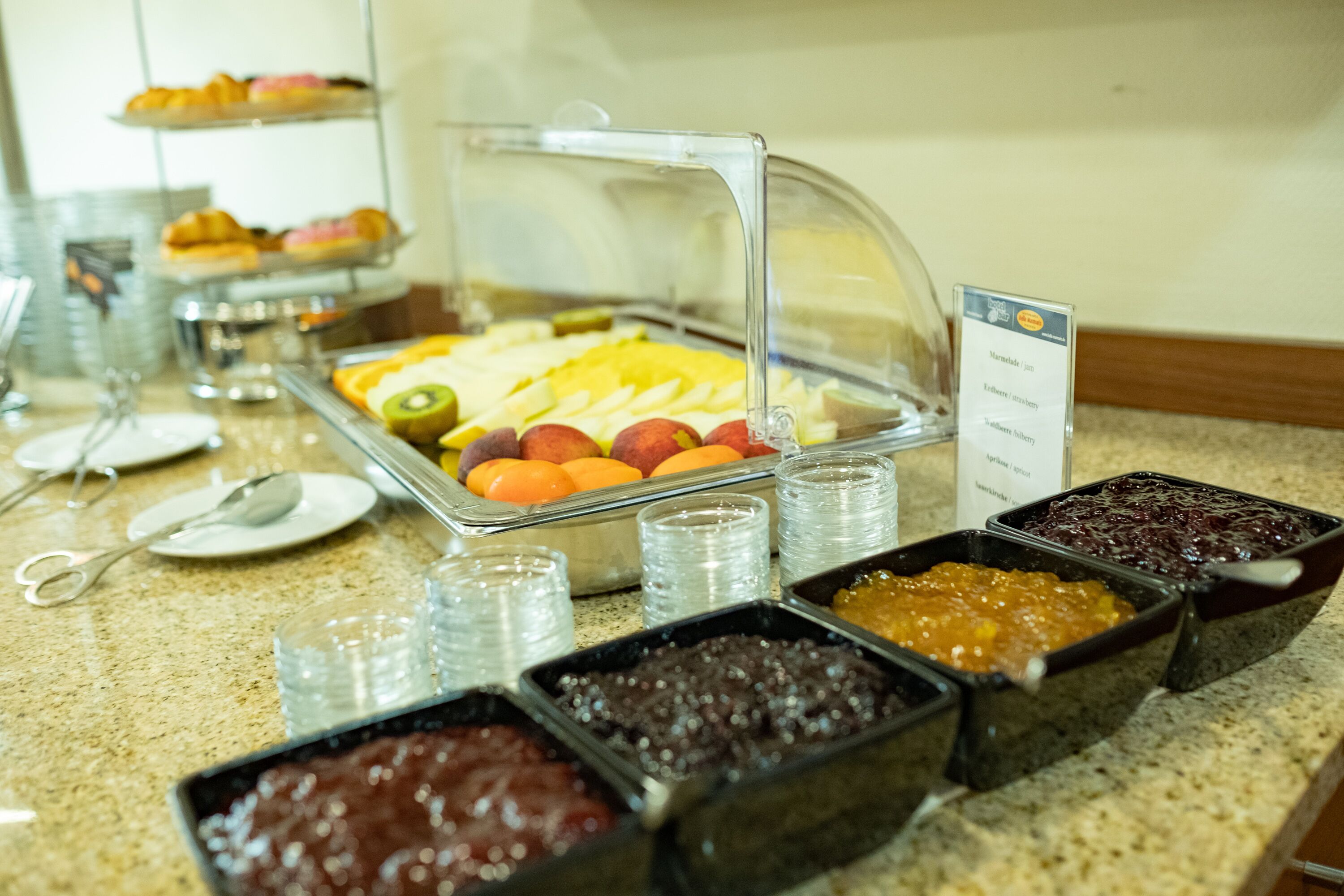 Un bufé con diversos alimentos, incluyendo frutas, pasteles y salsas.