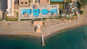 Vue aérienne d’un complexe hôtelier doté de plusieurs piscines, de chaises longues et d’une zone de plage.