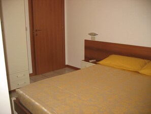 A bedroom with a bed, a wooden wardrobe, a nightstand, and a bedside table. - Bed & Breakfast Bompadre (Civitanova Marche)