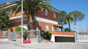 A multi-story building with a brick facade, a gated entrance, and a palm tree in the foreground. - Bed & Breakfast Bompadre (Civitanova Marche)