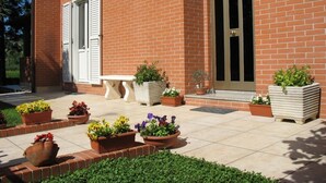 A brick building with a patio area featuring potted plants and a bench. - Bed & Breakfast Bompadre (Civitanova Marche)