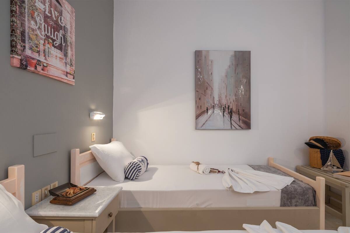 Un dormitorio ordenado con cama, mesitas de noche y una obra de arte colgada en la pared.
