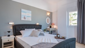 Un dormitorio ordenado con una cama grande, mesitas de noche, una lámpara de noche, un reloj de pared y una ventana con cortinas.