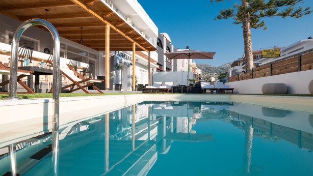 Zona de piscina con sillas de descanso y un pérgola de madera.